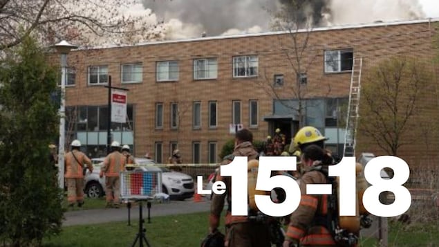 Un immeuble ravagé par les flammes est entouré par des pompiers.