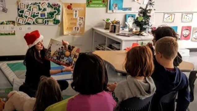 Des élèves autour d'une enseignante en train de leur faire la lecture.