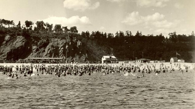 Le plaisir de se baigner dans le fleuve entre Québec et Sillery, en 1938. La foule est nombreuse, il y a plus de gens dans l'eau que sur la plage, et il fait clairement très chaud.
