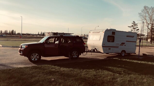 Un véhicule utilitaire sport remorquant une roulotte de camping de quelques mètres.