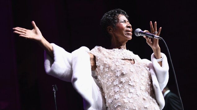 Aretha Franklin chante en écartant le bras droit Aretha Franklin chante en écartant le bras droit