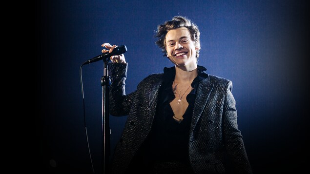 Harry Styles, souriant, devant un micro.