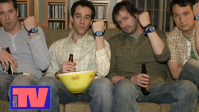 Les quatre personnages masculins de la série Les Invincibles assis sur un sofa, chacun brandit sa montre.