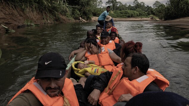 Des personnes migrantes avec des vestes de sauvetage dans une canoë. 