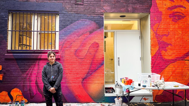 Une femme devant un mural.