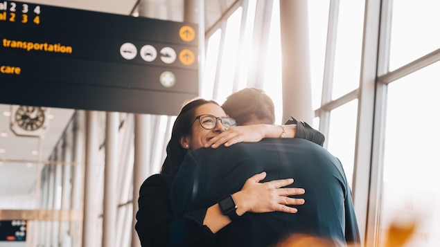 Un couple se serre dans les bras dans un aéroport.