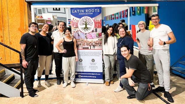 Un groupe de jeunes tient une banderole sur laquelle on peut lire "Latin Roots" (racines latines).