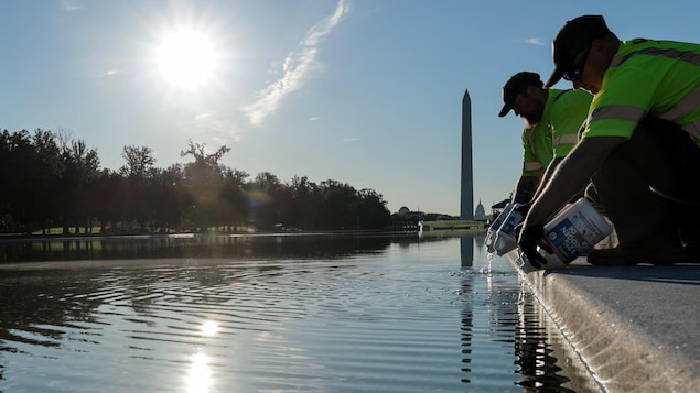 Des hommes déversent des bidons dans un bassin.