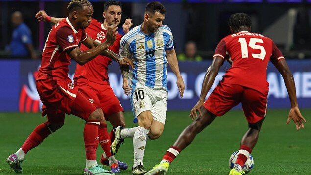 Lionel Messi attempting to dribble past the Canadian defense.