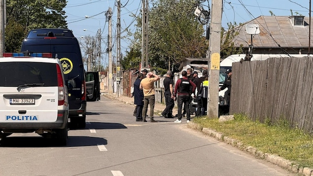 Des véhicules d'urgence et des enquêteurs dans une rue résidentielle. 