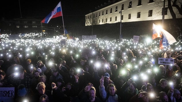 La nuit, une foule de manifestants brandit des drapeaux et des téléphones cellulaires allumés.