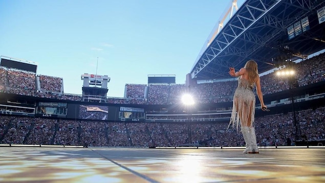 La chanteuse Taylor Swift danse lors d'un concert dans un stade. Elle porte une tenue argentée.