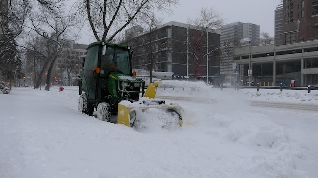 Une machine déblaie la neige sur un trottoir à Winnipeg jeudi 14 avril 2022.