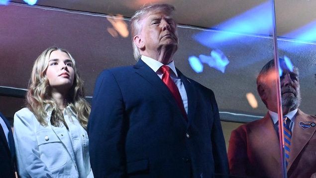 Donald Trump entouré de sa petite-fille Kai et de James Dolan, se tiennent debout pendant l'hymne national.