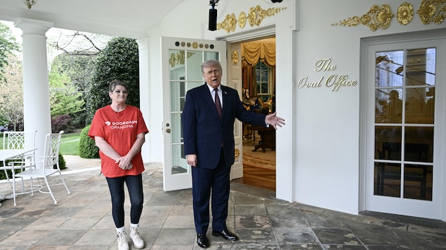 Devant la porte extérieure du bureau ovale de la Maison-Blanche, une femme st tient aux côtés de Donald Trump pendant que celui-ci répond à des journalistes.