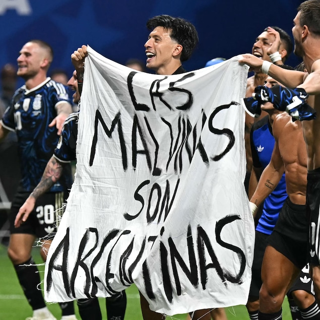 Des joueurs de l'équipe argentine de soccer, sur le terrain, avec une banderole où on peut lire « Las Malvinas son argentinas ».