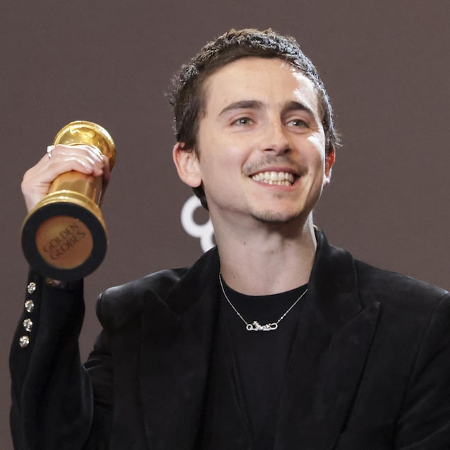 Il tient son trophée dans la main droite.