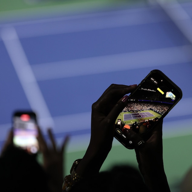 Des téléphones filment un terrain de tennis.