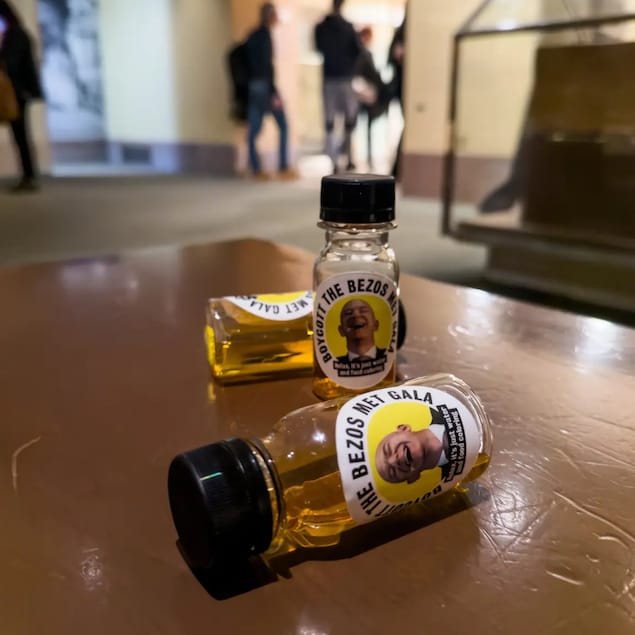 Sur une table, des bouteille avec une étiquette arborant le visage hilare de Jeff Bezos contiennent un liquide qui s'apparente à de l'urine.