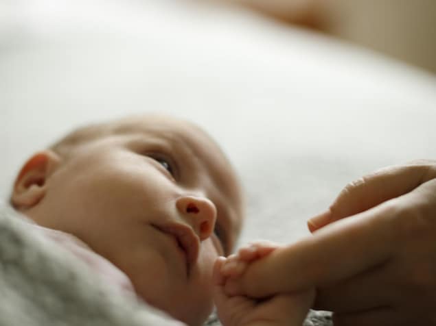 Un bébé tient le doigt de sa mère.