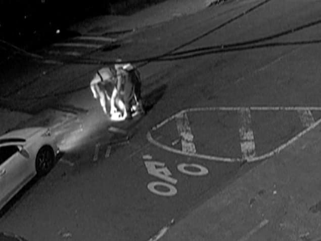 Un groupe d'hommes se glissant dans une bouche d'égout, filmé par une caméra de surveillance.