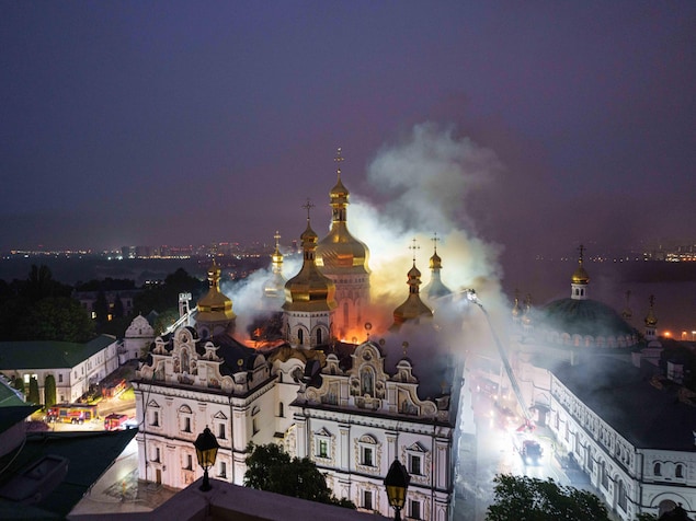 De nuit, vue aérienne de pompiers qui luttent contre l'incendie d'une cathédrale.
