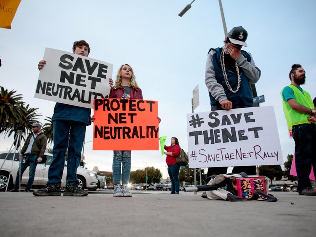Des personnes tiennent des pancartes qui disent, en anglais, « protégez la neutralité d'Internet » ou « Sauvez Internet ».