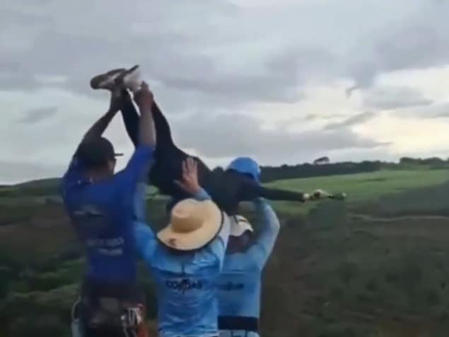 Trois hommes portent à bout de bras une femme munie d'un casque.
