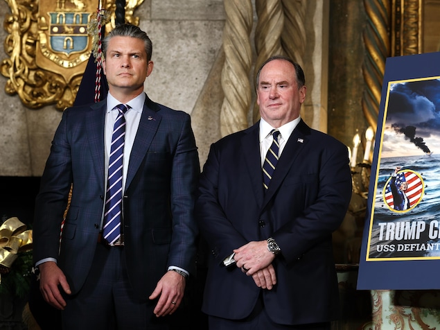 Pete Hegseth et John Phelan aux côtés d'une affiche faisant la promotion d'un navire de guerre.
