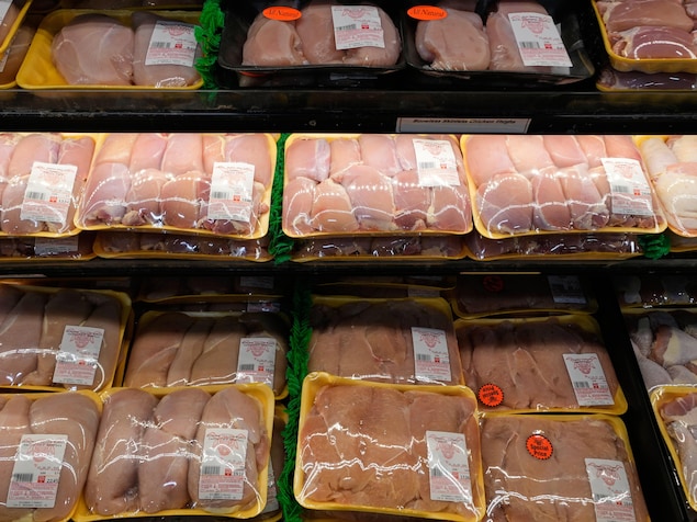 Des paquets de hauts de cuisse de poulet dans une épicerie.