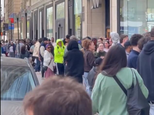 Une foule en ligne sur un trottoir.