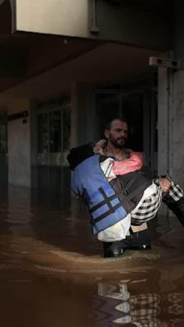 A volunteer rescues Carmelina Castro, 79, from a flooded area in the Cidade Baixa neighborhood in Porto Alegre, Rio Grande do Sul state, Brazil, on May 8, 2024. The worst natural calamity ever to hit the state of Rio Grande do Sul has claimed at least 95 lives, with 372 people reported injured and 131 still missing, according to the civil defense force that handles disaster relief. (Photo by Anselmo CUNHA / AFP) (Photo by ANSELMO CUNHA/AFP via Getty Images)