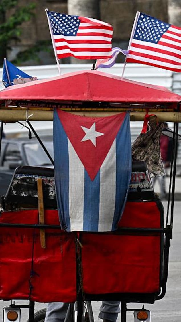 Dans une rue, un tricycle décoré des drapeaux américain et cubain à La Havane.