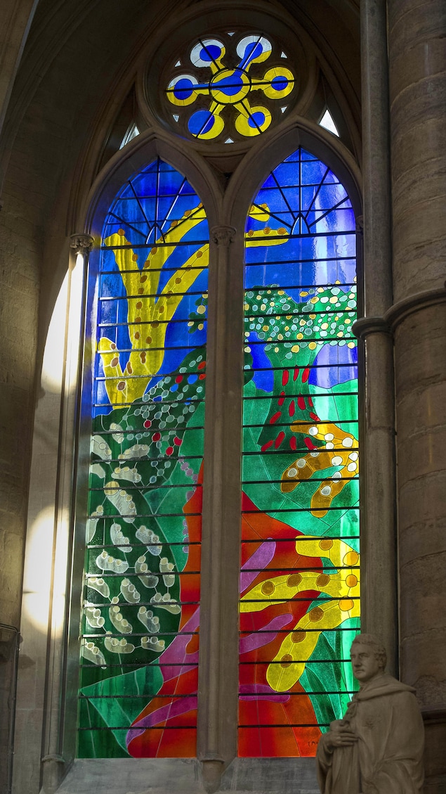 Dans une abbaye, un vitrail dépeint une scène champêtre.