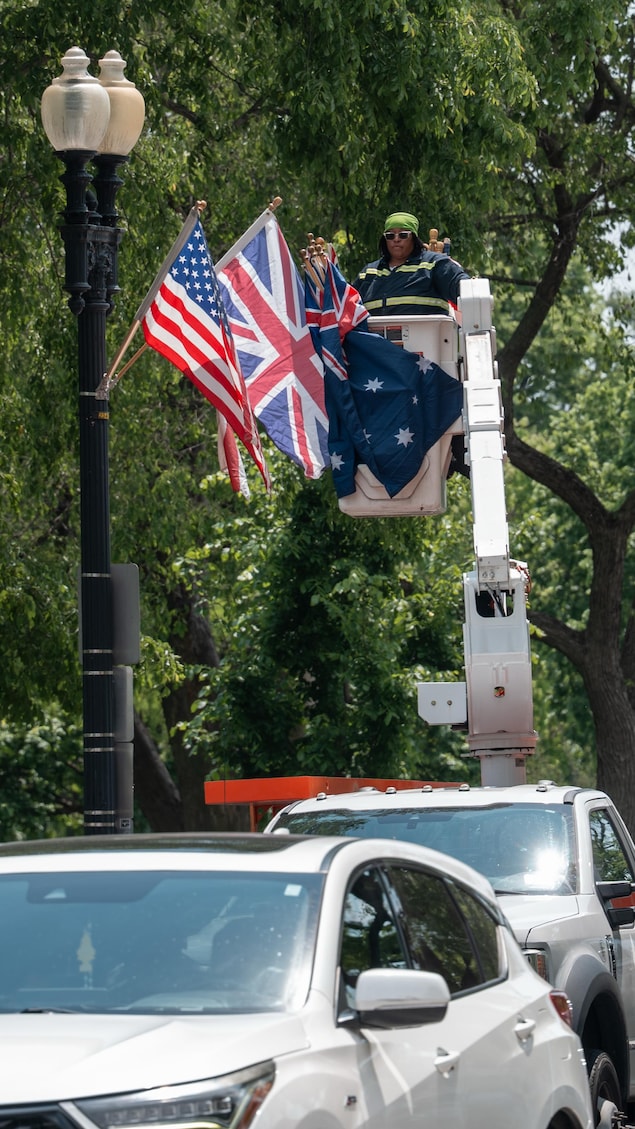 Une femme dans une nacelle remplace un drapeau australien par un drapeau britannique.