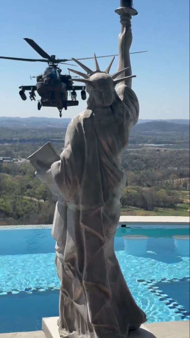 Un hélicoptère militaire derrière une réplique de la statue de la Liberté.