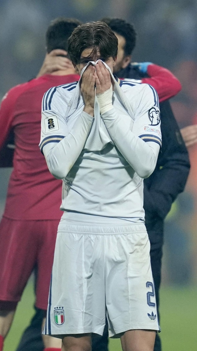 Un homme tire son chandail contre son visage à deux mains, l'air déçu.