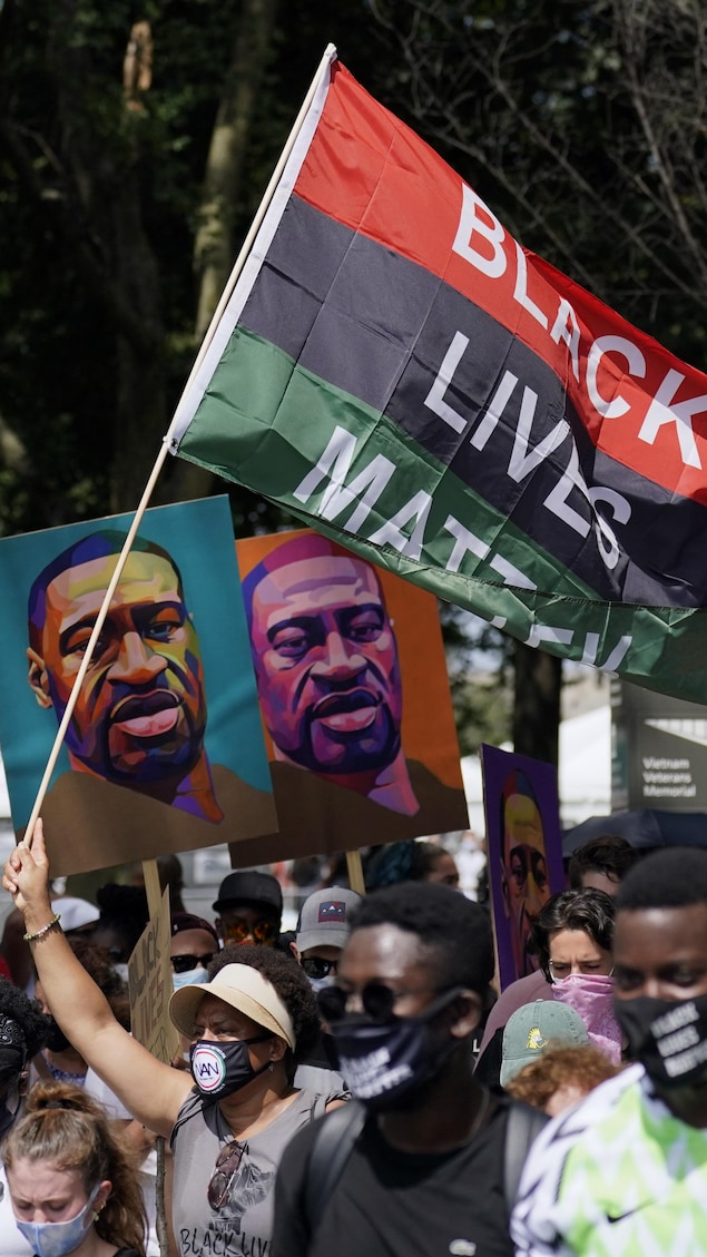 Des manifestants brandissent la photo de George Floyd et des banderoles sur lesquelles il est écrit : Black Lives Matter