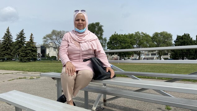 امرأة جالسة على مقعد في ملعب لكرة القدم.