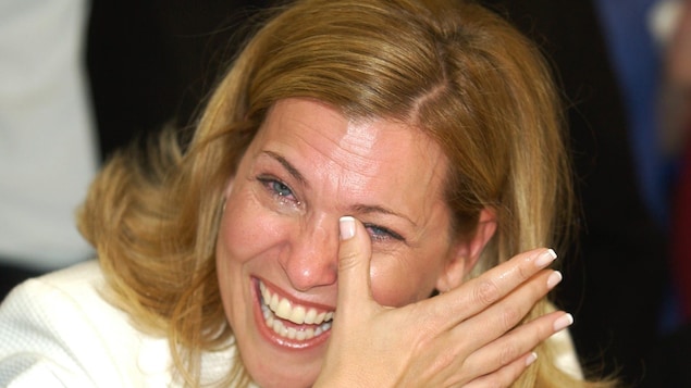 Une femme essuie ses larmes en souriant.
