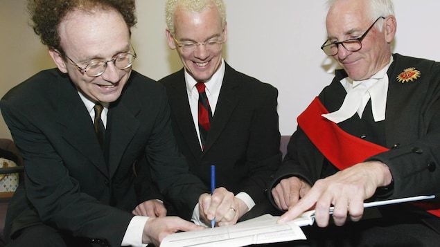 Michael Leshner et Mike Stark en complet veston-cravate signent un document officiel devant un juge.