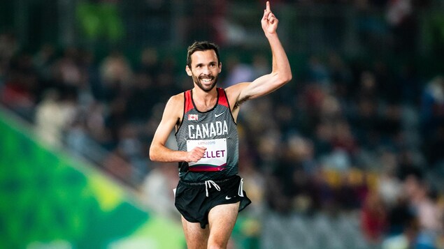 Un coureur de para-athlétisme effectue une course et pointe vers le ciel.