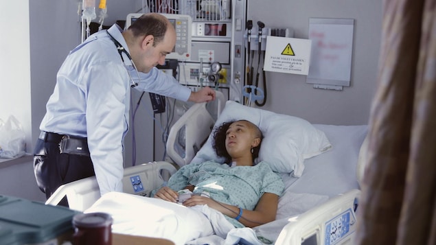 Un docteur parle à une patiente sur son lit d'hôpital.
