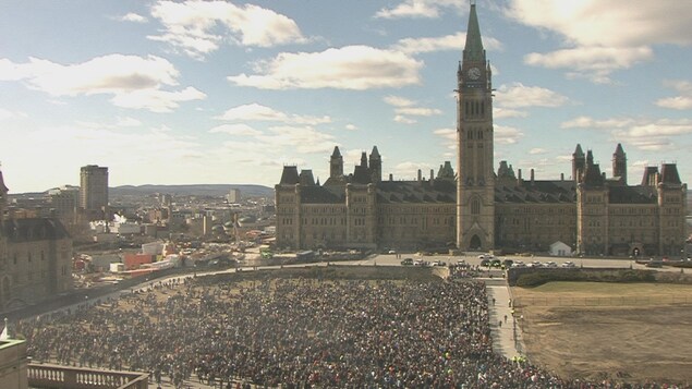 Des gens sont sur la pelouse devant le parlement.