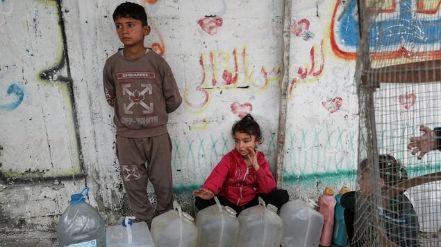 Palestinian children gather near containers used for water in Gaza City on April 6. Roughly 40 per cent of drinking water production facilities in Gaza currently remain functional, according to UNICEF.