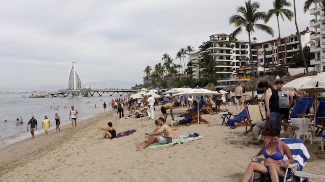 Tourists are seen along the beach in Puerto Vallarta, Mexico, in December 2015. The resort town on Mexico's Pacific coast is the home of the notorious Jalisco New Generation Cartel, which officials say has been defrauding the owners of local time-shares. 