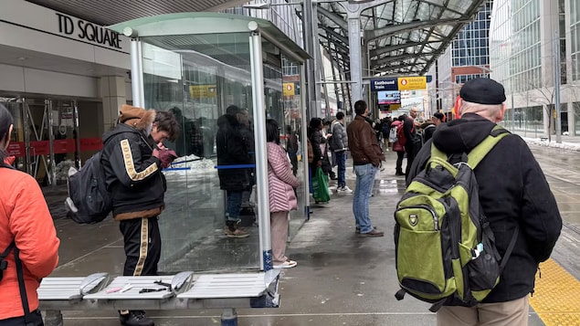 Un homme fume sur un quai bondé du CTrain, dans le centre-ville de Calgary, en avril 2026. 