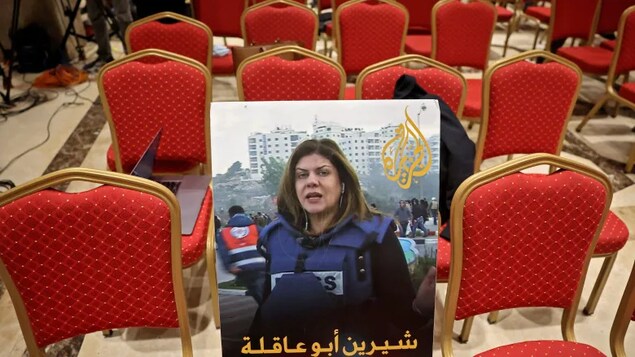 A photo of slain correspondent Shireen Abu Akleh, with a caption in Arabic reading 'Shireen Abu Akleh, the voice of Palestine,' is shown among reporter chairs on July 15 in the city of Bethlehem in the West Bank. (Ahmad Gharabli/AFP/Getty Images)