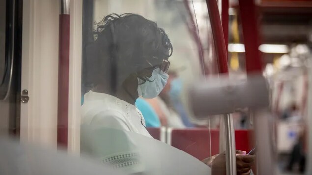 Isang babae na naka-mask sa loob ng subway train.