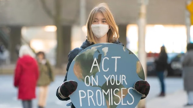 A youth climate protester stands at the Queen Street West and Bay Street intersection in downtown Toronto on Friday, March 19, 2021. 